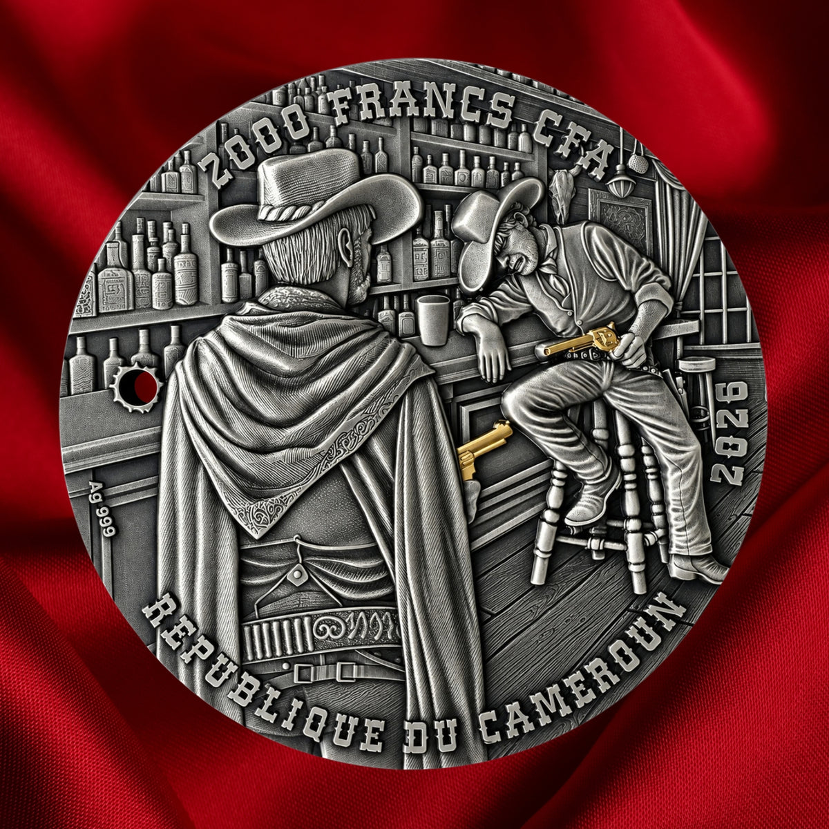 A circular silver-toned commemorative coin or medallion featuring two illustrated bar patrons with gilded guns aimed at each other, with raised text reading '2000 FRANCS - CFA and REPUBLIQUE DU CAMEROUN