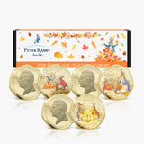 Peter Rabbit Tales of Autumn three-coin set showing coloured reverses and King Charles III obverses in front of illustrated packaging.