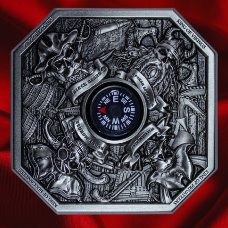 Front view on red satin: KOMSCO 2024 The Kings of Pirates silver stacker featuring four pirate portraits around a central compass, with antiqued nautical details against red satin.