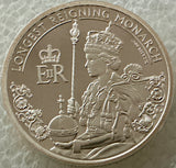 Silver coin featuring a monarch with decorative elements and text on a textured background