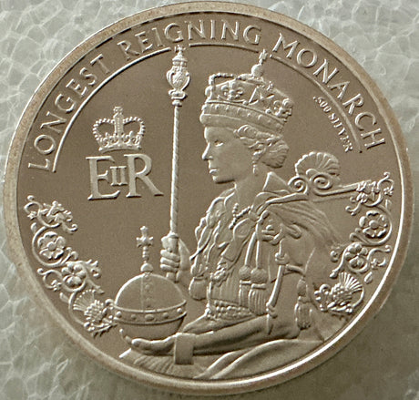 Silver coin featuring a monarch with decorative elements and text on a textured background