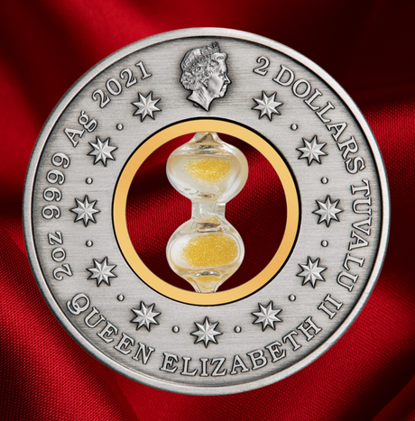 A round silver commemorative coin featuring a central clear glass hourglass filled with gold sand, set against a red fabric background. The coin is inscribed with '2 DOLLARS TUVALU II QUEEN ELIZABETH II 9999 Ag 2021' and features a profile of Queen Elizabeth at the top.