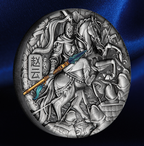 An oval silver-toned relief medallion featuring a detailed historical battle scene with a warrior on horseback holding a spear, set against a dark blue satin background.