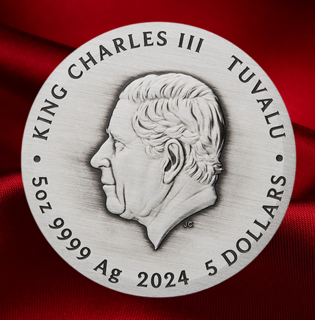 A round silver-toned commemorative coin or medallion featuring a profile portrait of King Charles III, with engraved text reading 'KING CHARLES III', 'TUVALU', '5 OZ 9999 Ag', and '2024 5 DOLLARS', set against a draped red fabric background.