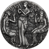 A silver coin with a detailed relief design featuring three ancient goddesses, Clotho, Lachesis, and Atropos, from Greek mythology, within a grove setting.