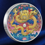 A round silver collectible coin featuring a highly detailed, colorful Chinese dragon design on a dark blue satin fabric background.