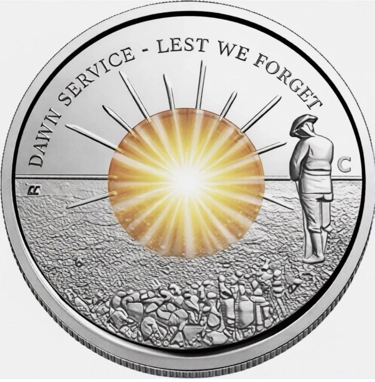 Silver coin with a sunburst design and text 'Dawn Service - Lest We Forget' on a white background