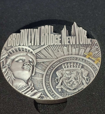 Silver coin with Brooklyn Bridge design on a dark background