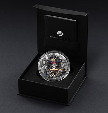Silver coin with intricate design in a black box on a dark background
