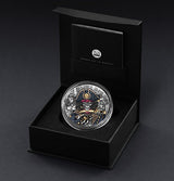 Silver coin with intricate design in a black box on a dark background
