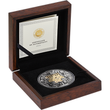 Silver coin with gold accents in a wooden box with a certificate of authenticity.