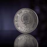 Silver coin with detailed design on a reflective surface
