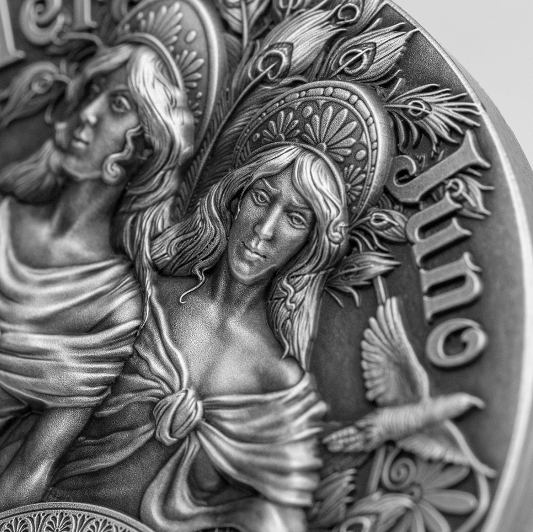 Close-up photo of the antique silver coin focusing on the sculpted faces of Hera and Juno. Their classical Greek and Roman profiles feature sharp, high-relief details highlighting their expressions, hair textures, and crowns against the dark,antiqued silver background.