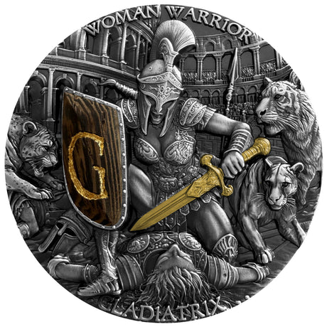 A circular silver-toned coin or medallion featuring a detailed gladiator scene with a warrior holding a sword and shield marked with a gold letter G, surrounded by animals and an arena background. The text 'WOMAN WARRIOR' and 'GLADIATRIX' is visible around the border.