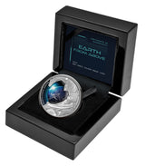 Niue 2022 Earth From Above silver proof coin showing Earth reflected in an astronaut’s visor sitting in it's open black laquer case. The Case is facing toward the left.