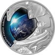 A silver proof coin with an astronaut's helmet design reflecting the Earth from space.