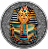 A close-up view of the detailed reverse side of the Niue 2022 2-ounce silver coin. The high-relief antiqued design centers on the legendary death mask of Pharaoh Tutankhamun, intricately embellished with selective yellow-gold gilding and deep blue accents on the nemes headdress. The top features the protective uraeus cobra and vulture symbols, while a traditional artificial beard accents the chin. The entire mask is framed by an etched border of historic Egyptian hieroglyphics.