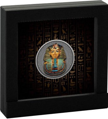 A studio product shot displaying the 2022 Niue Tutankhamun's Mask 2 oz silver coin mounted in its official exhibition setup. The thick, antiqued coin is positioned vertically inside a fitted black insert that acts as a secure display stand. This presentation highlights the high-relief depth, the 24k selective gold plating, and the colorful digital printing of the pharaoh mask, creating an elegant collector's exhibit.